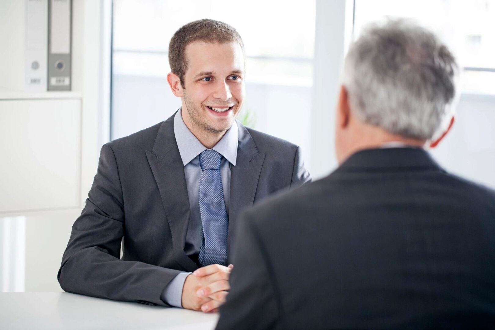A man in suit and tie shaking hands with another person.