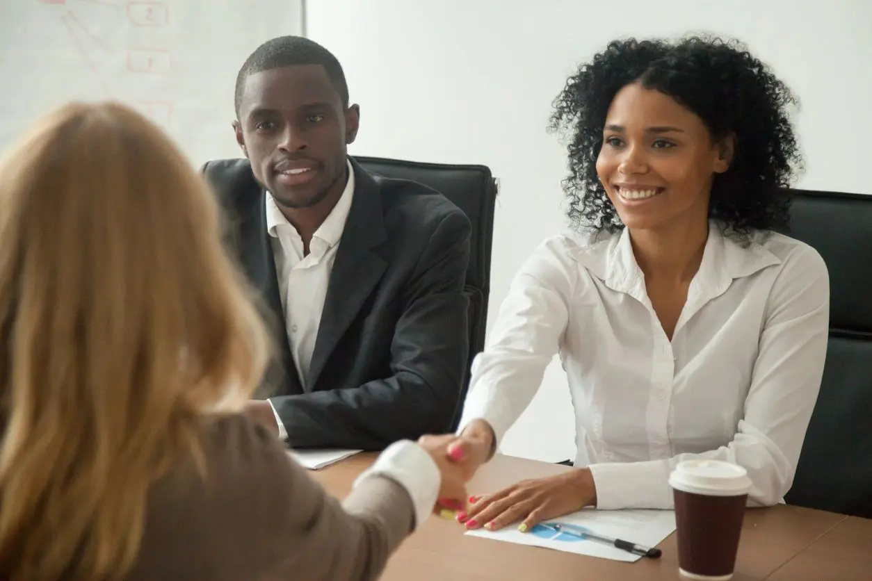 A woman shaking hands with another person at a table.